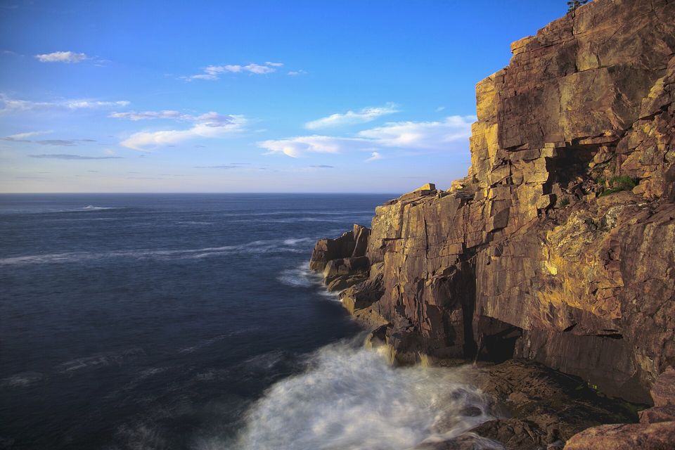 Pink granite cliffs glowing in low sun above a dark sea