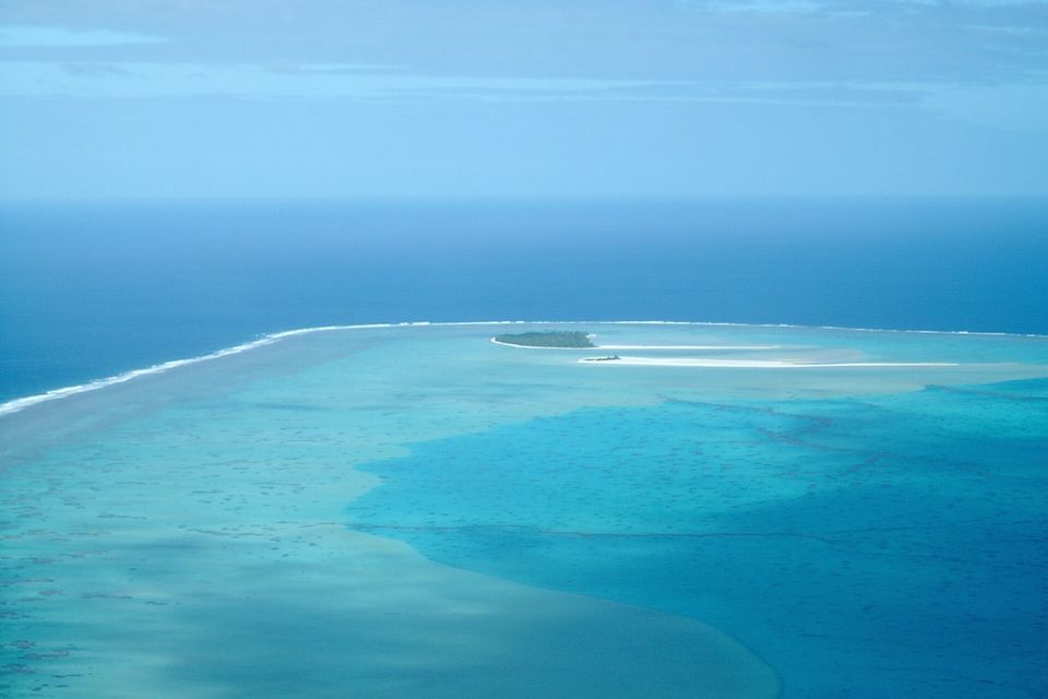 Aitutaki's barrier reef from the air, with surf on the ocean side and pale lagoon shallows inside