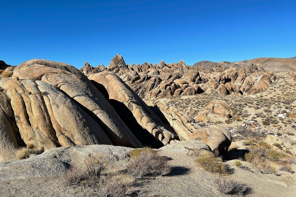 Rounded, layered granite fins and spires under a clear blue sky