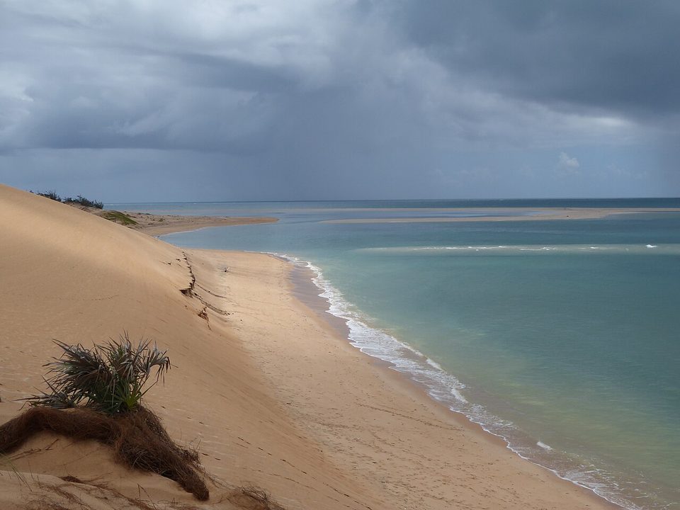 Sandbars and a dune edge under a dark storm sky
