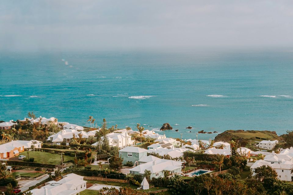 White stepped limestone roofs and pastel houses running down to a blue sea in hazy light