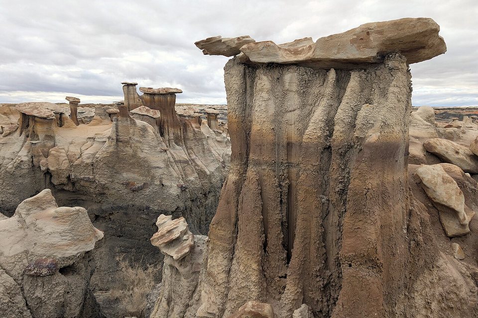 A flat stone slab capping a fluted clay pillar under an overcast sky