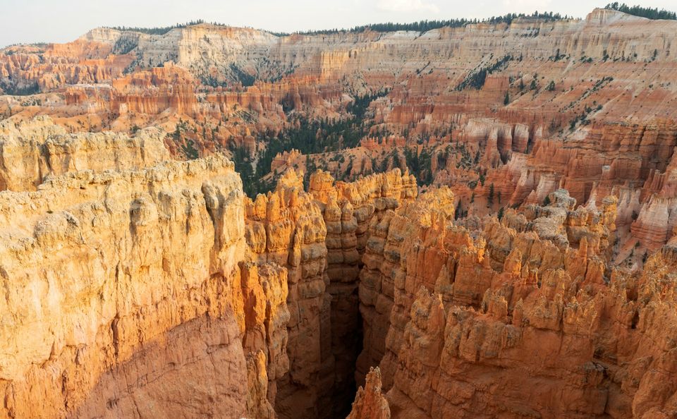 A narrow slot between tall rock walls seen from the rim in low evening light