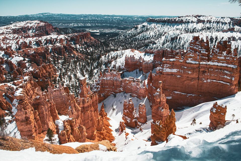Orange rock spires dusted with snow among pines under a blue sky