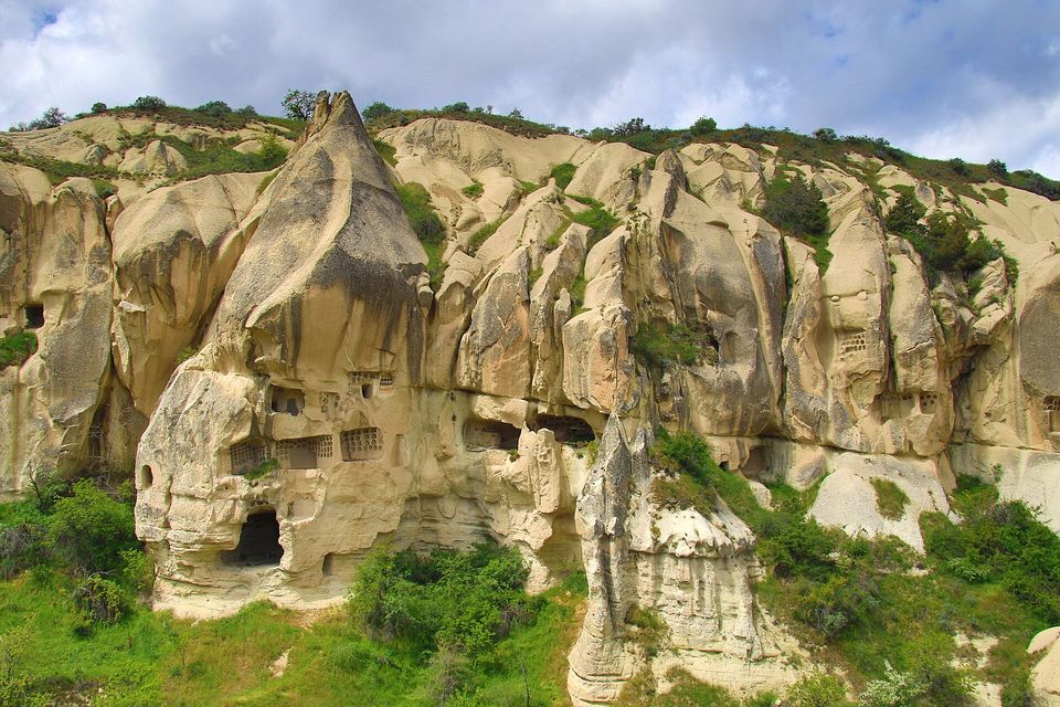 A rock face pierced by doorways and small square windows