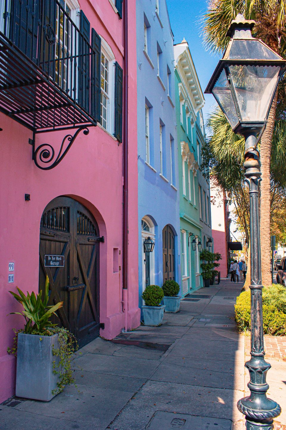 A row of pastel-painted houses, a pink one nearest, with a street lamp beside it