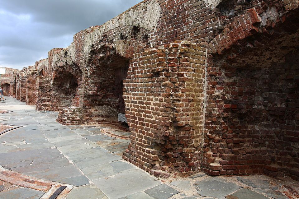 Shattered red-brick casemate arches inside a fort wall under a blue sky