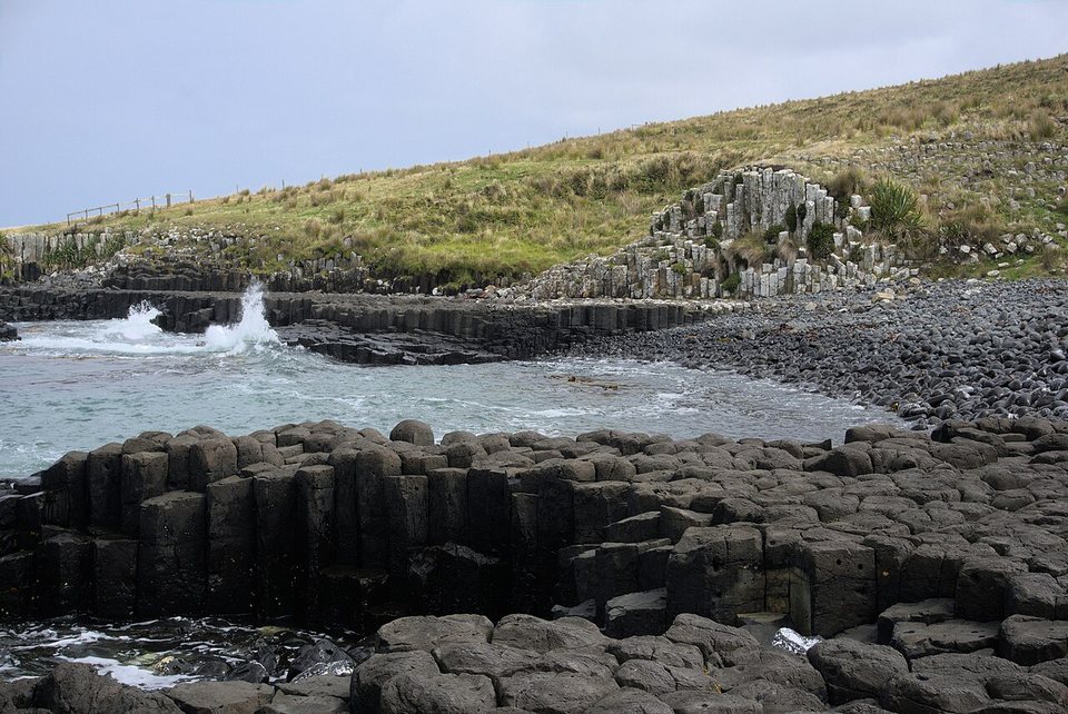 Grey basalt columns beside a surf-washed shore