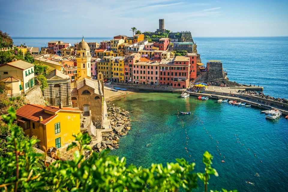 A harbour village with a church tower and a round tower on a headland above the sea