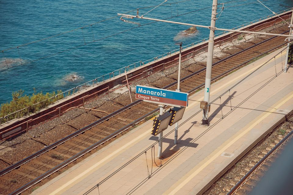 A railway platform and tracks beside the open sea, with a station name sign