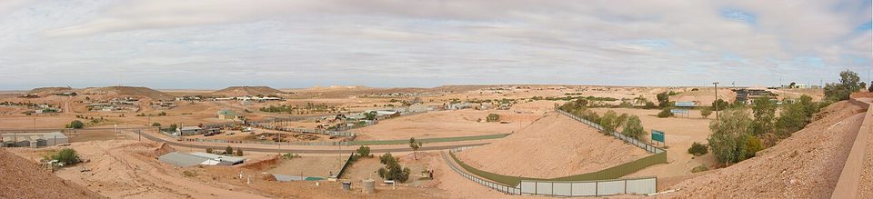 A wide panorama of a low desert town among pale mullock heaps under a big sky