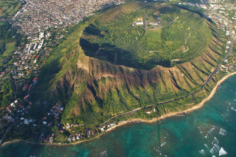 Looking down into a green volcanic crater from the air