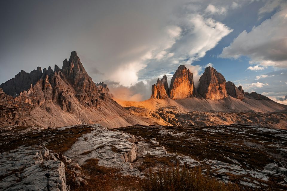 Three huge limestone towers glowing orange beyond pale rock slabs