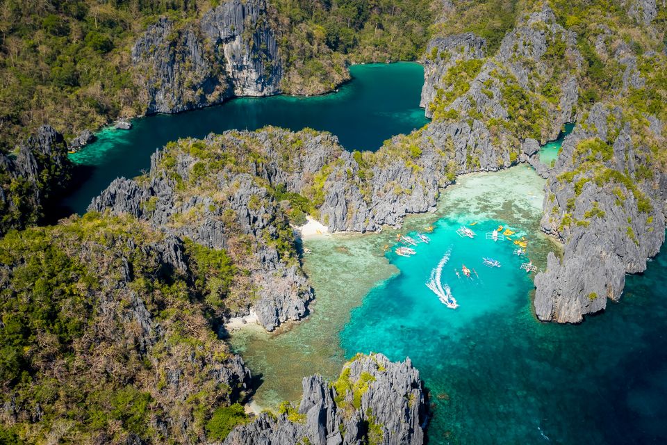 Green lagoons threading between jagged limestone islands in Bacuit Bay, seen from the air
