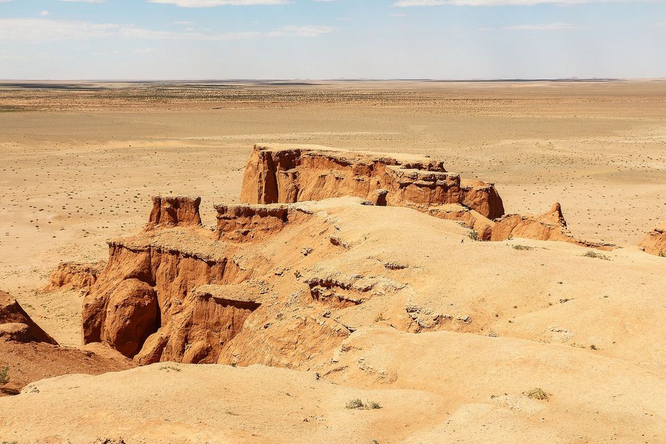 Red-orange sandstone cliffs above a gravel desert plain