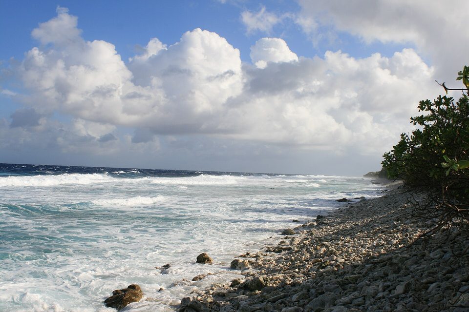 Surf breaking on a reef beside a beach of coral rubble