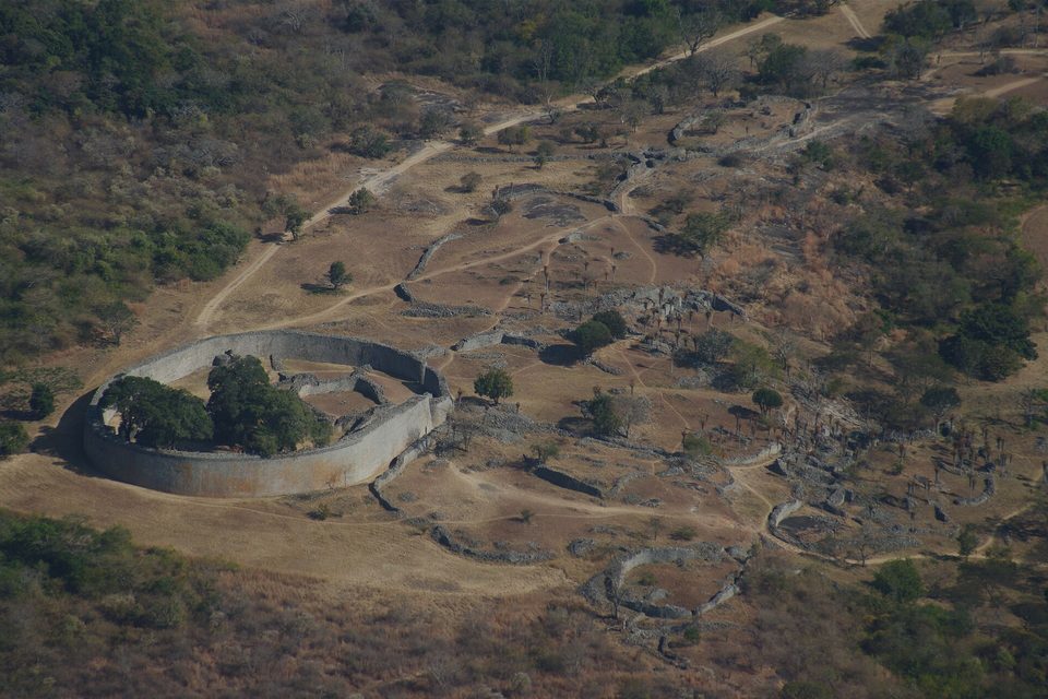 The Great Enclosure and the ruins of the valley below the hill seen from above, with trees inside the elliptical wall