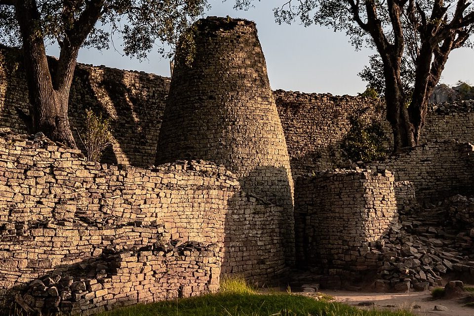 A solid conical tower of dry-stone granite with no door, inside the Great Enclosure, in low gold light