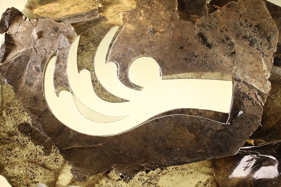 Translucent brown mica sheets on a light table, a cut-out shape left as an empty outline