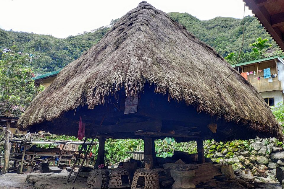 A steep thatched Ifugao house raised on wooden posts in Batad village