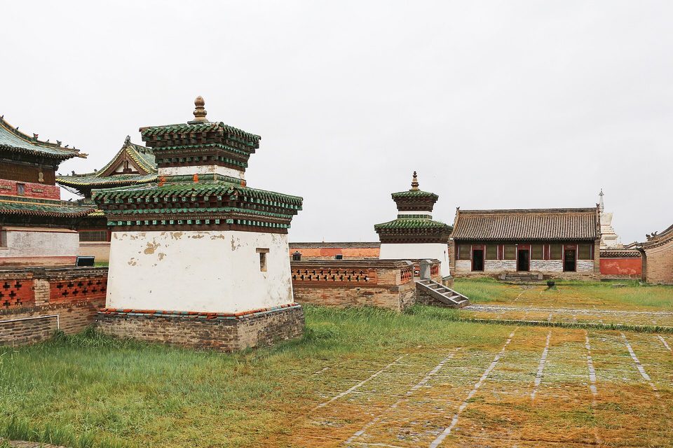 Stupas with green-tiled roofs among the temples of a monastery under a white sky
