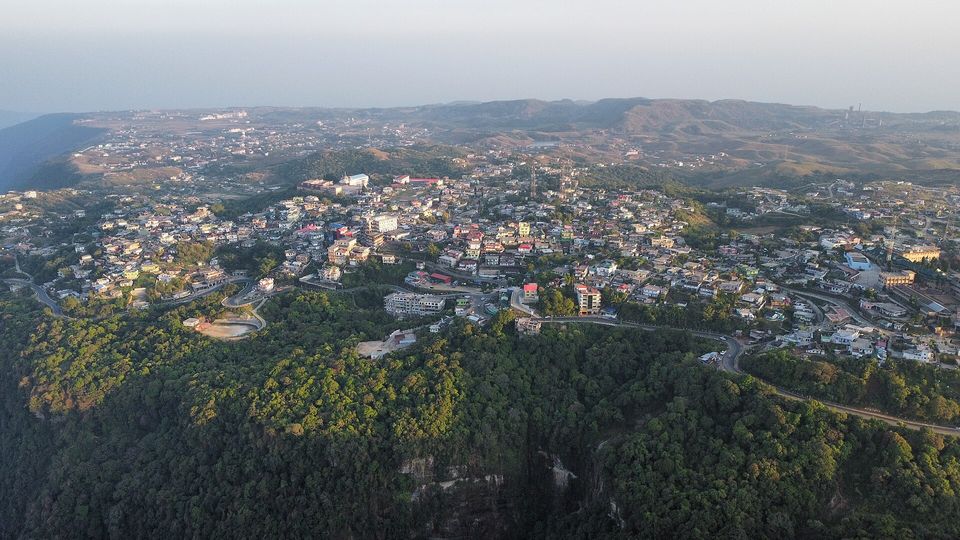 Aerial view of a hillside town of coloured roofs with forest in the foreground