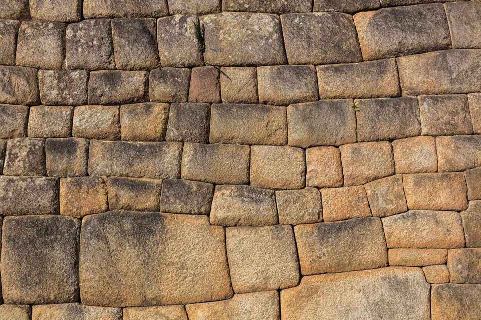 A close view of a dry-stone wall of tightly fitted rectangular blocks laid in courses, with no mortar between them