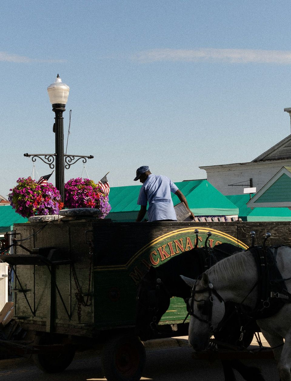 A horse-drawn wagon with painted lettering and flower baskets on a lamp post beside it, seen from above