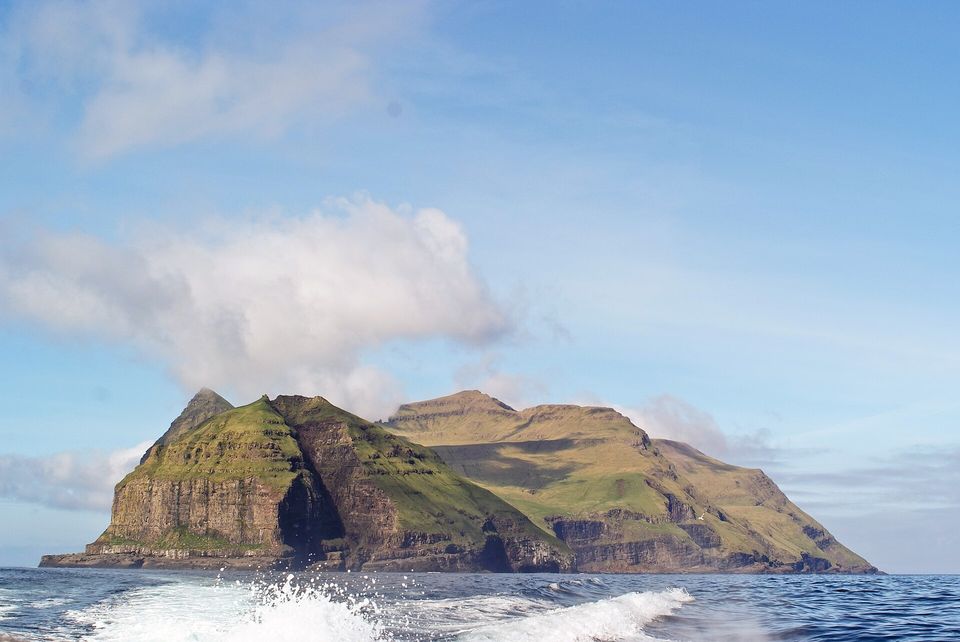 A steep green island rising from the sea on the horizon