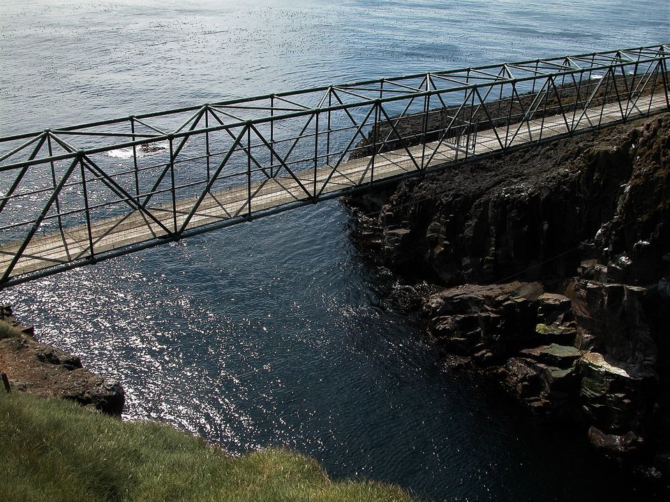 A narrow footbridge spanning a deep sea gorge