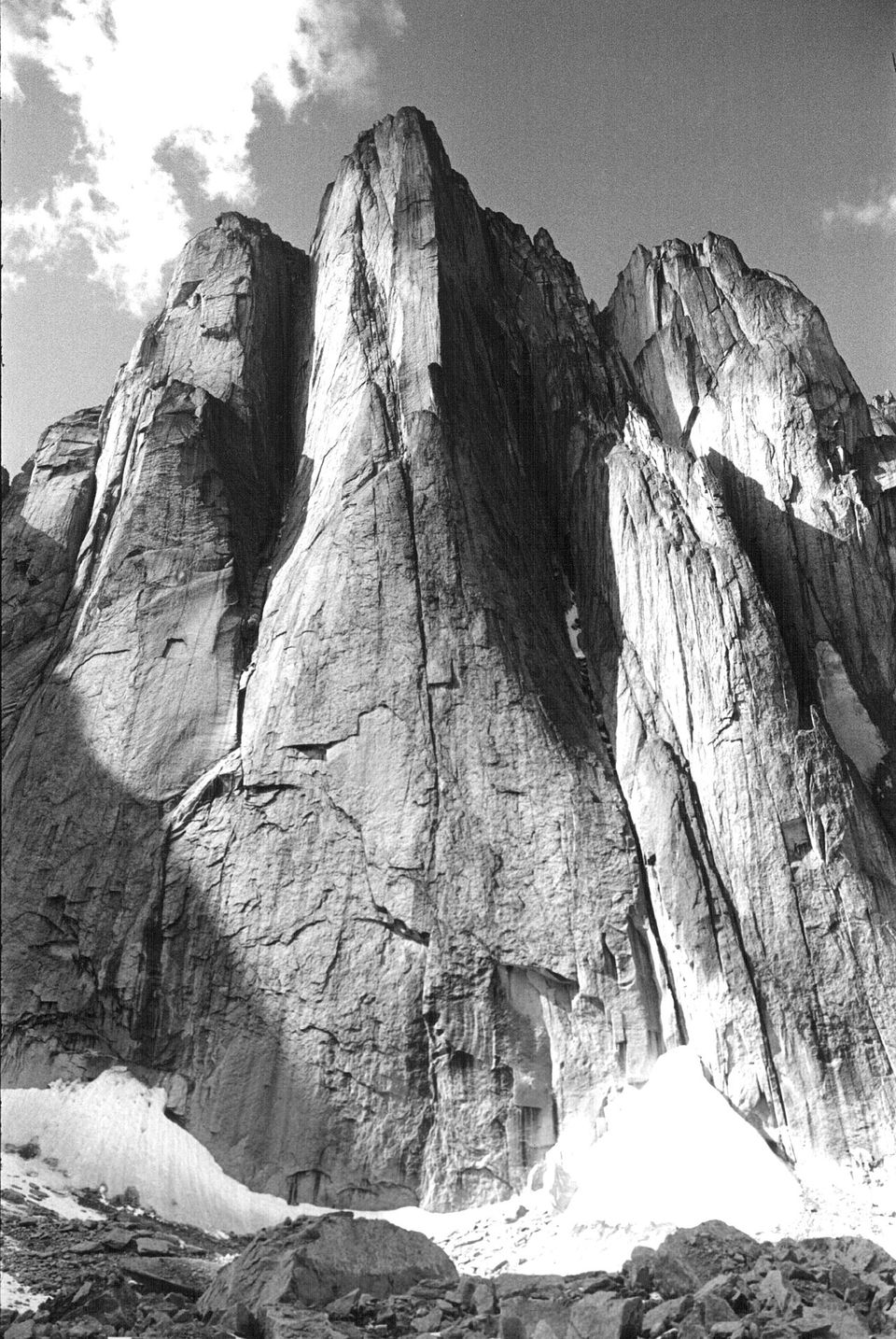 A black-and-white view of a sheer granite tower above a meadow