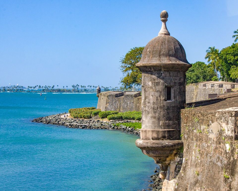 A domed stone sentry box jutting from a fortress wall over the water, the wall running on beyond