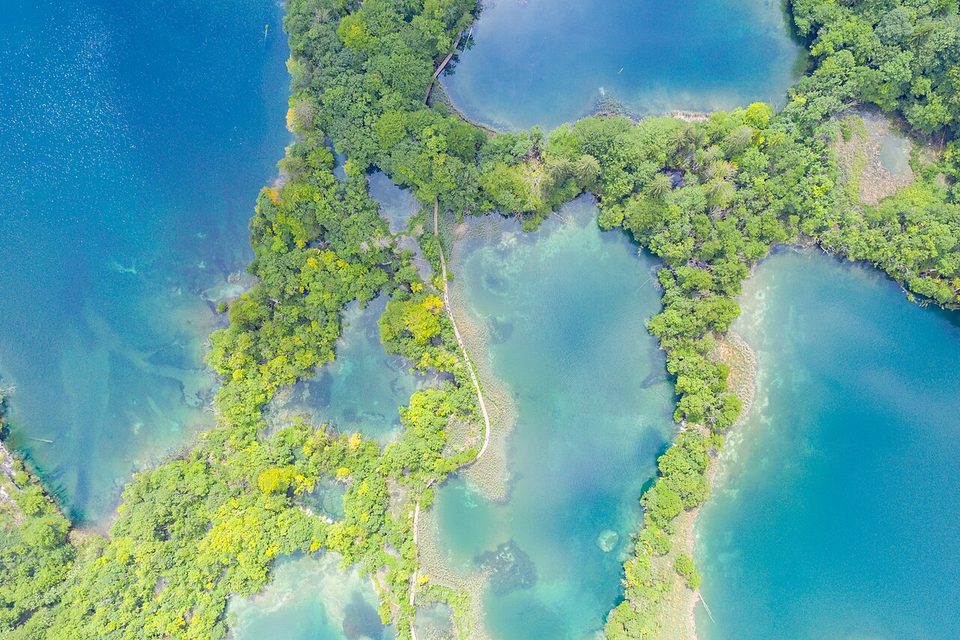 Straight-down view of tufa barriers dividing one lake from the next, a boardwalk crossing them