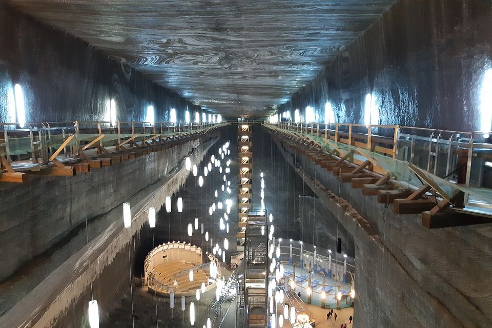A long vaulted ceiling of grey salt, swirled with darker bands, runs above timber galleries and strings of hanging lamps