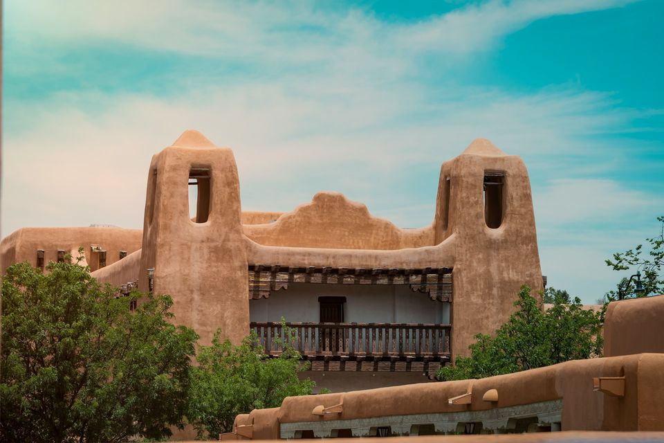 A twin-towered, earth-coloured Pueblo Revival building under a blue sky