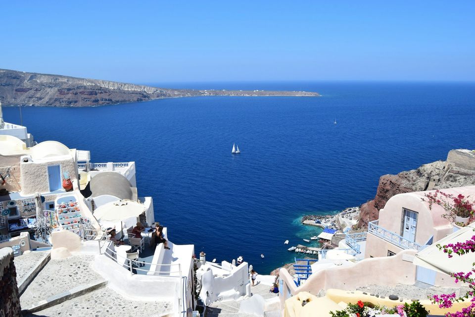A flooded volcanic caldera with a small harbour far below and an island across the water