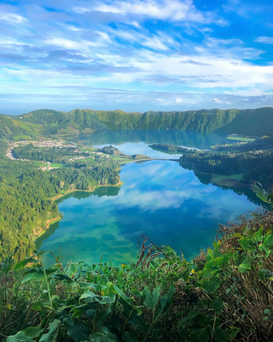 Two crater lakes, one green and one blue, side by side with a causeway between them