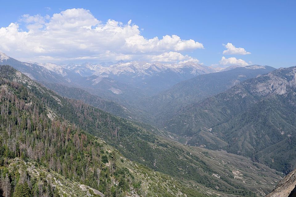 A wide granite-and-forest panorama to distant peaks