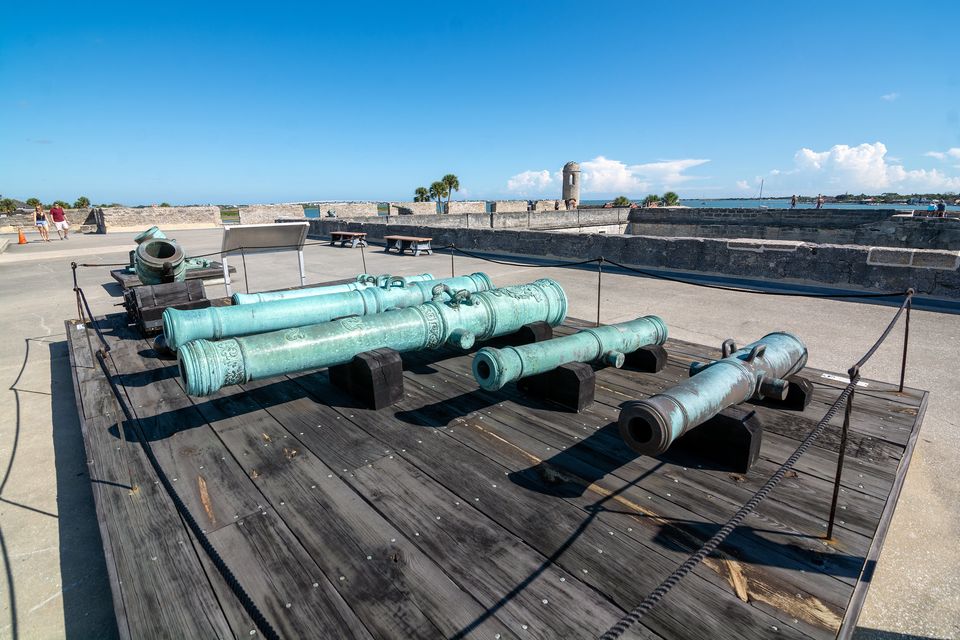 Bronze cannon on the gun deck of a fort, the bay and a sentry box beyond