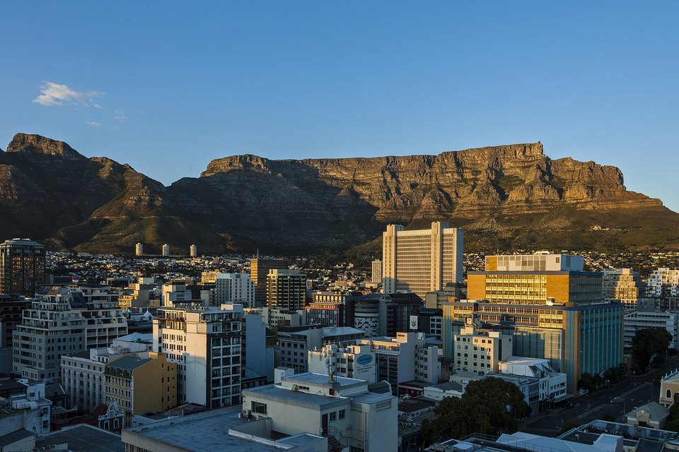 Warm dawn light on the long cliff face of Table Mountain above the office blocks of central Cape Town