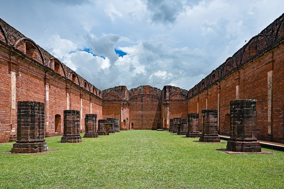 An unfinished church open to the sky: two long walls of arched windows and rows of column stumps on the lawn