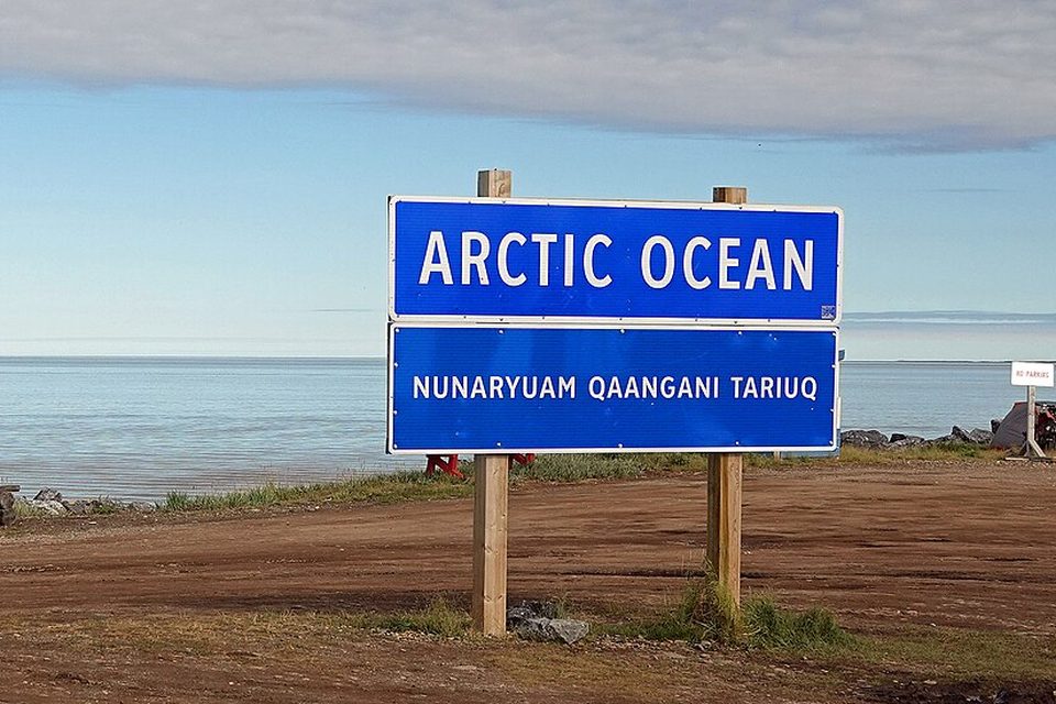 A sign at the end of a gravel road facing the Arctic Ocean