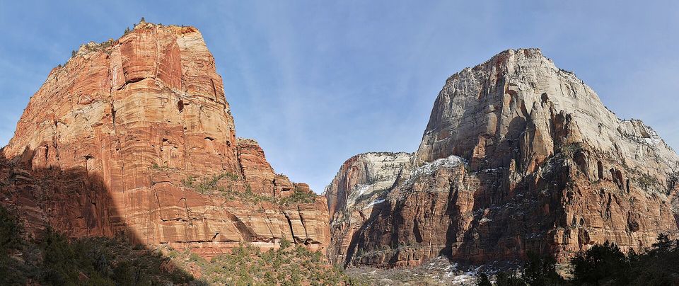 A red sandstone fin beside a pale snow-dusted dome of rock under a blue sky